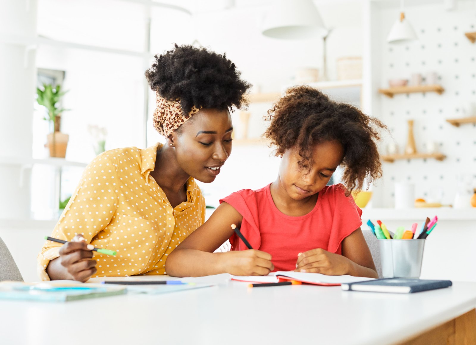 An adult supporting a young child as she writes